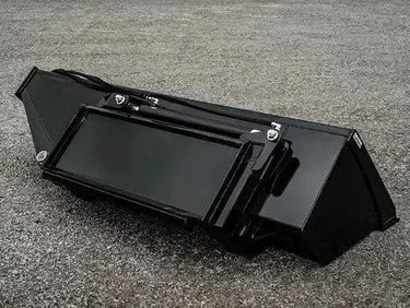 A black rectangular box sitting on top of a gravel road.
